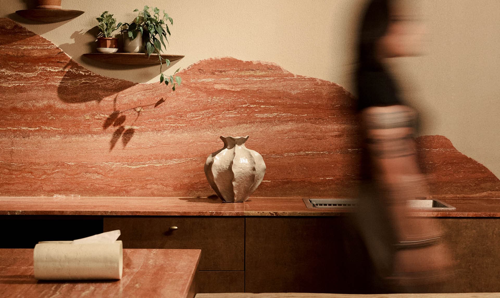 Red travertine material composition with a handmade ceramic vessel