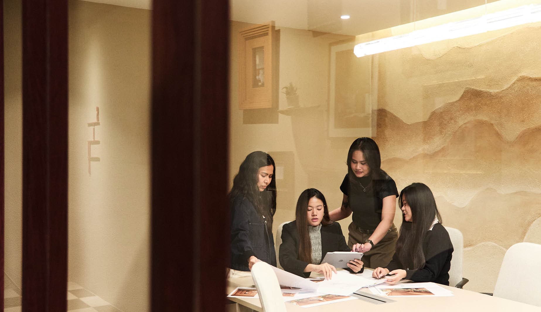 Glass-walled meeting room with a layered earth-tone relief wall