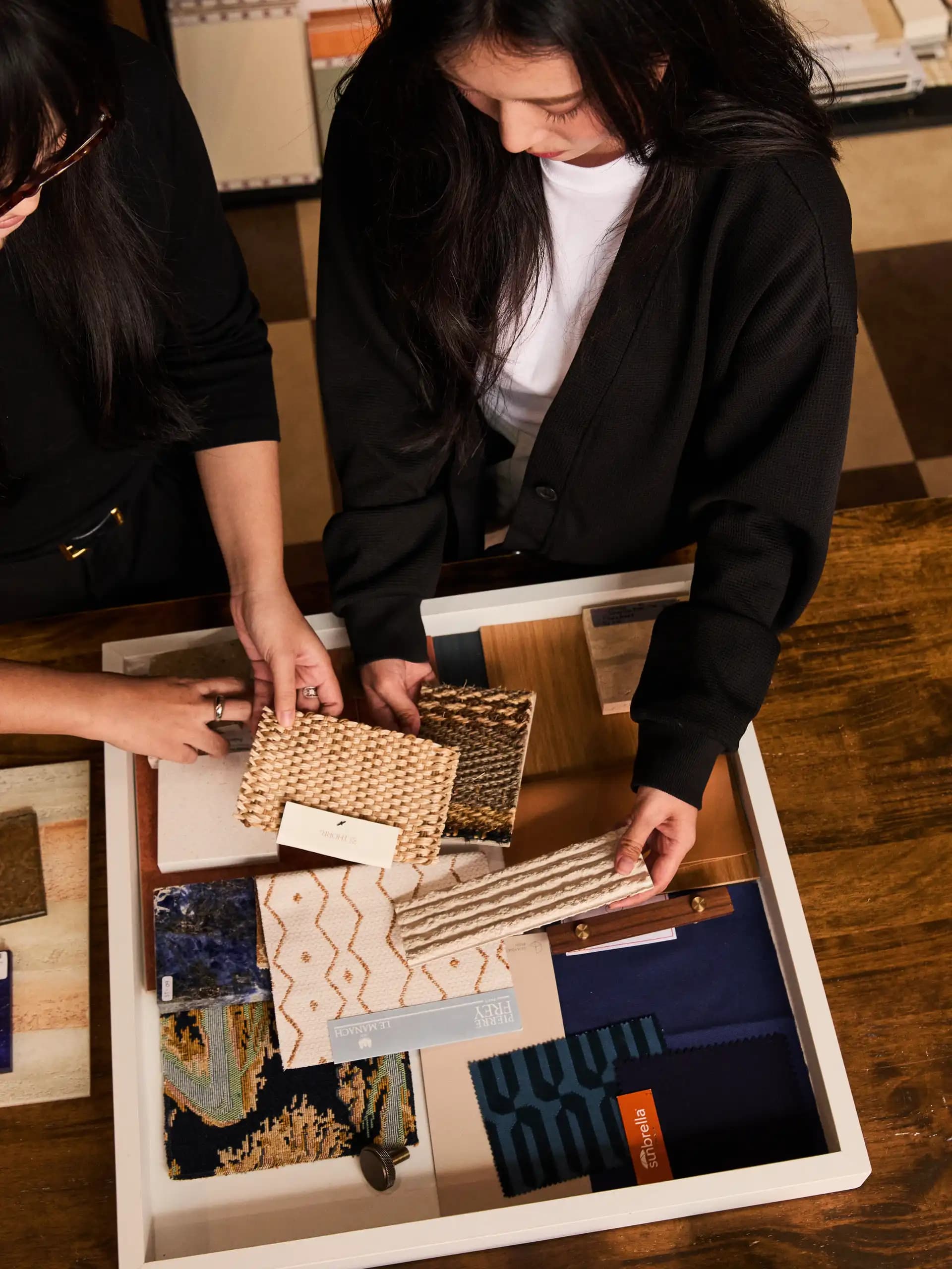 Designers selecting material swatches, tiles, and fabrics for moodboard