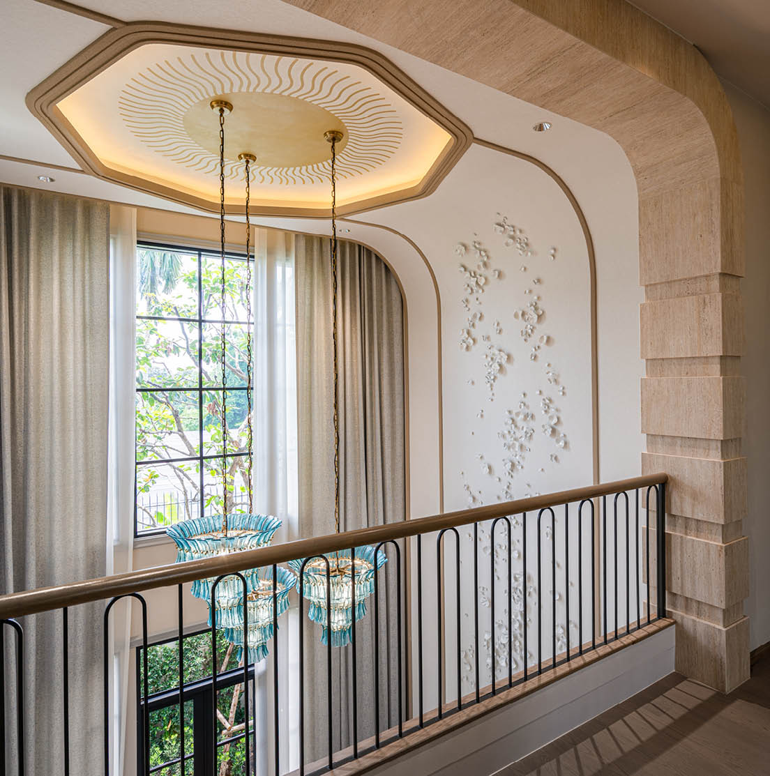 Double-height entrance hall with sculptural wall and glass chandeliers